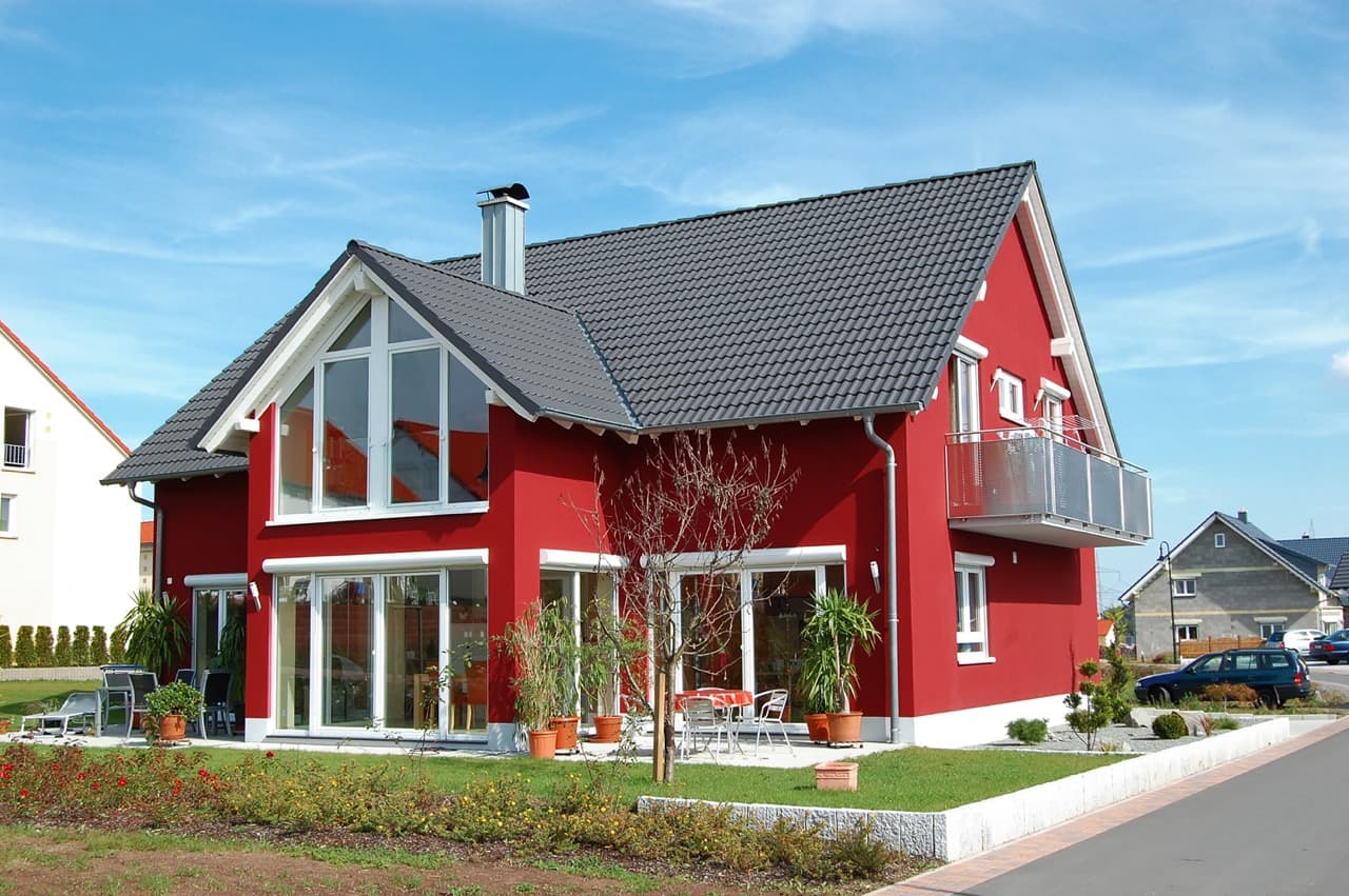 Ein Rotes Haus mit einem gepflegten Garten im Vordergrund.